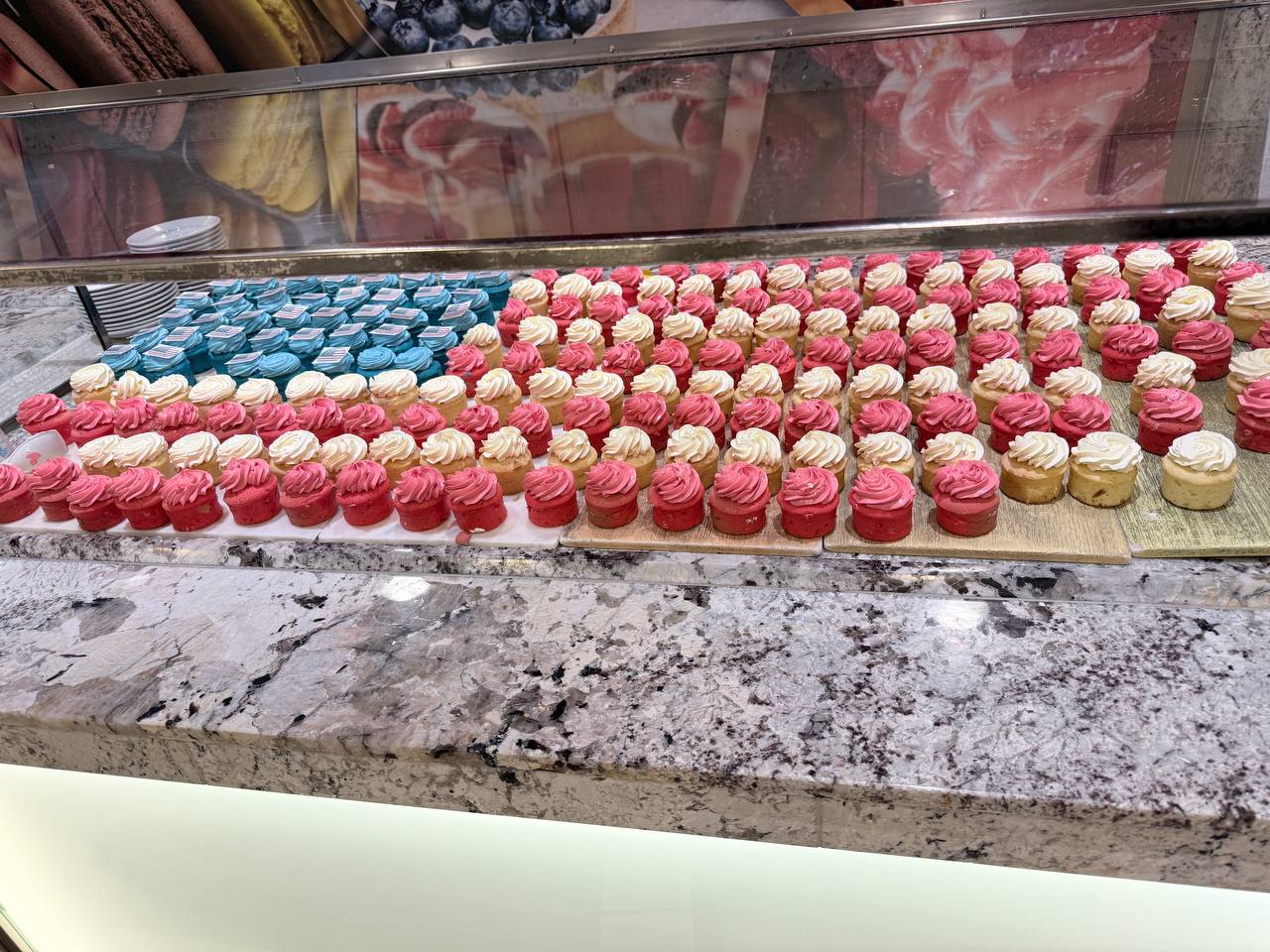 Cupcakes in a bakery display celebrating 4th July - blue, pink, white and red cupcakes on a granite countertop