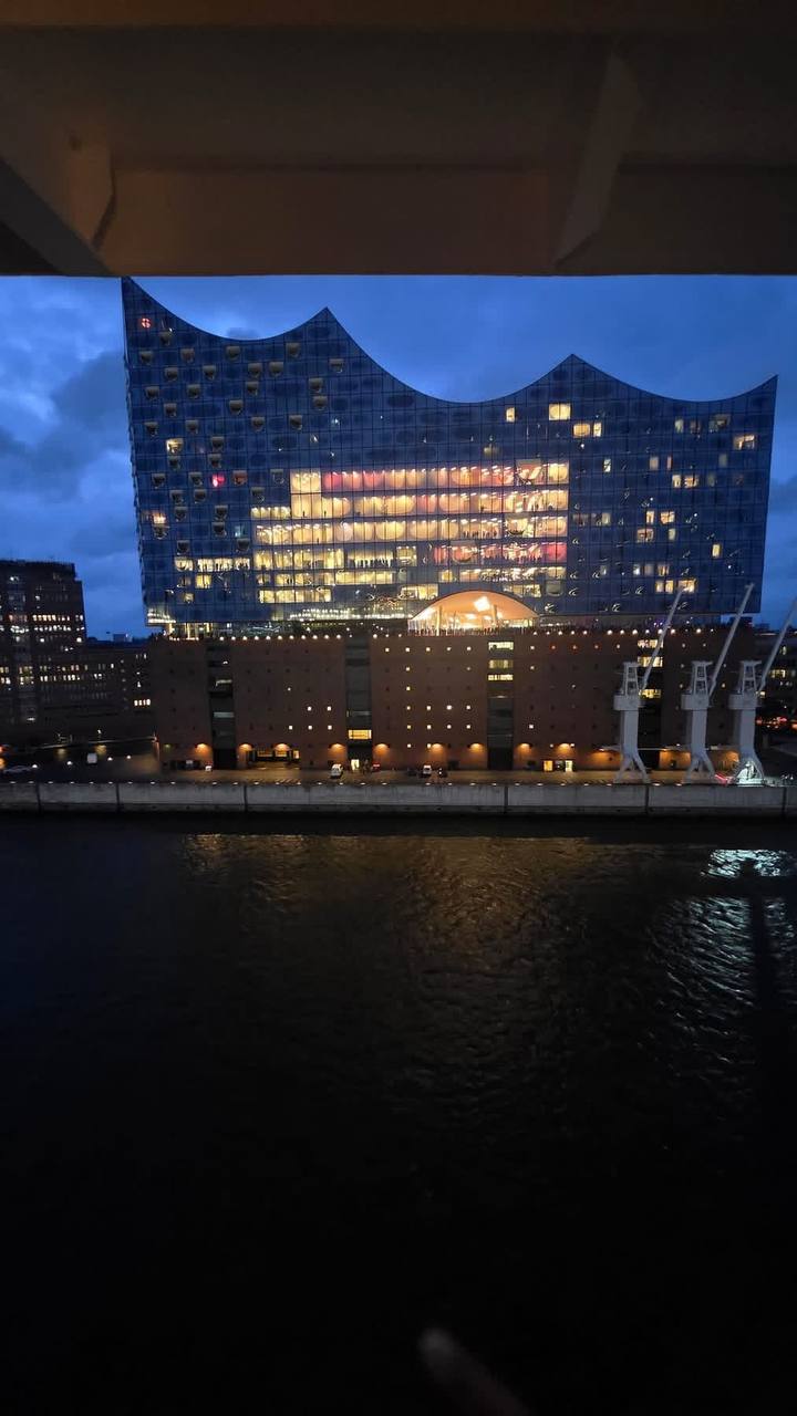 Elbphilharmonie illuminated at night with glowing windows reflected in the Elbe river