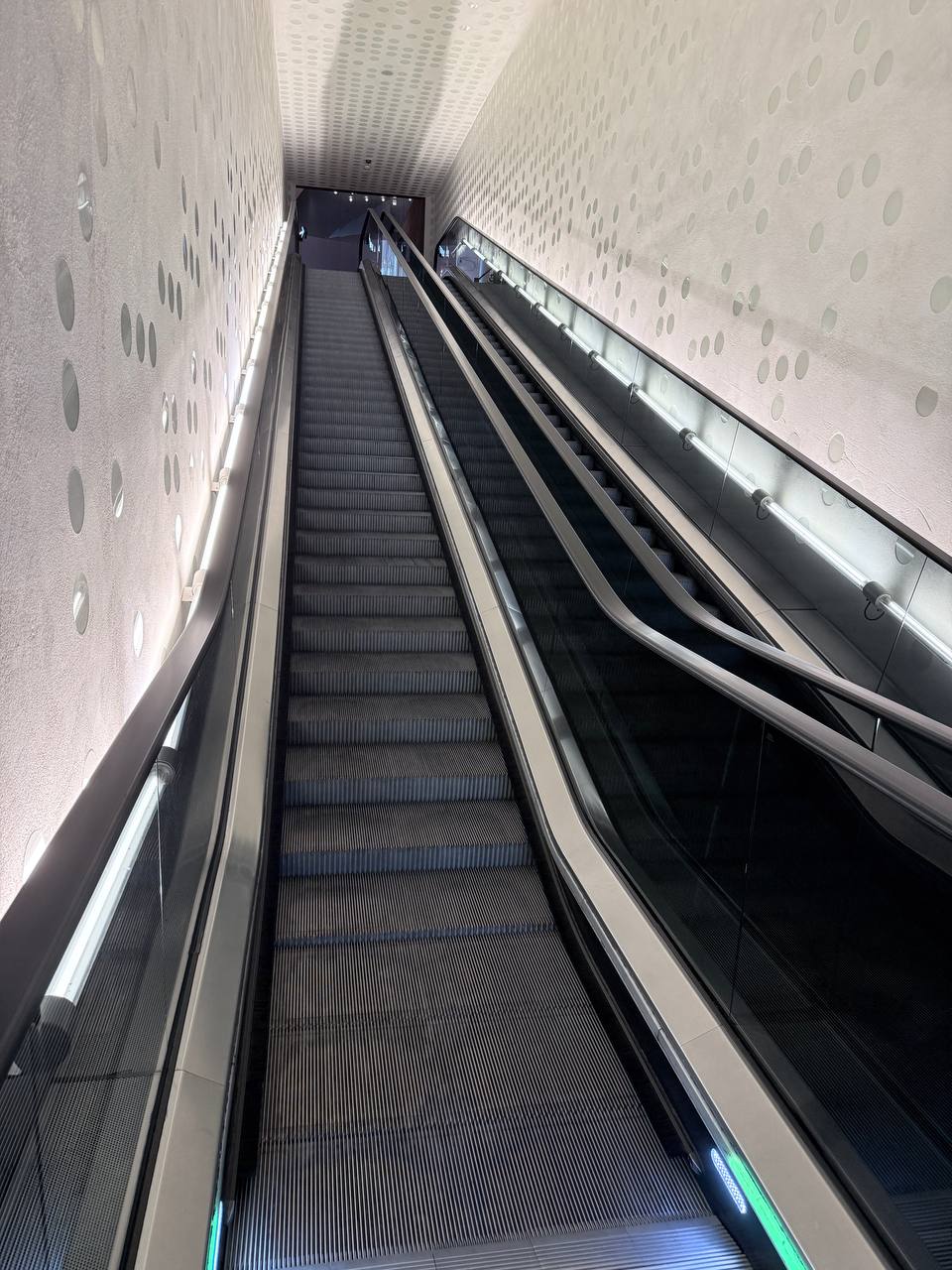 Symmetrical escalator system viewed from below with green LED strips