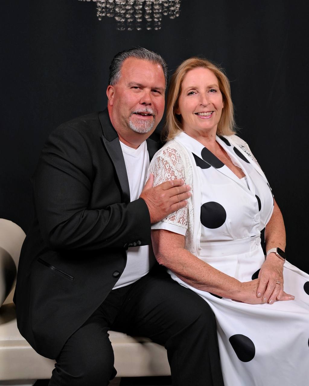 Studio portrait of couple on white bench with black background