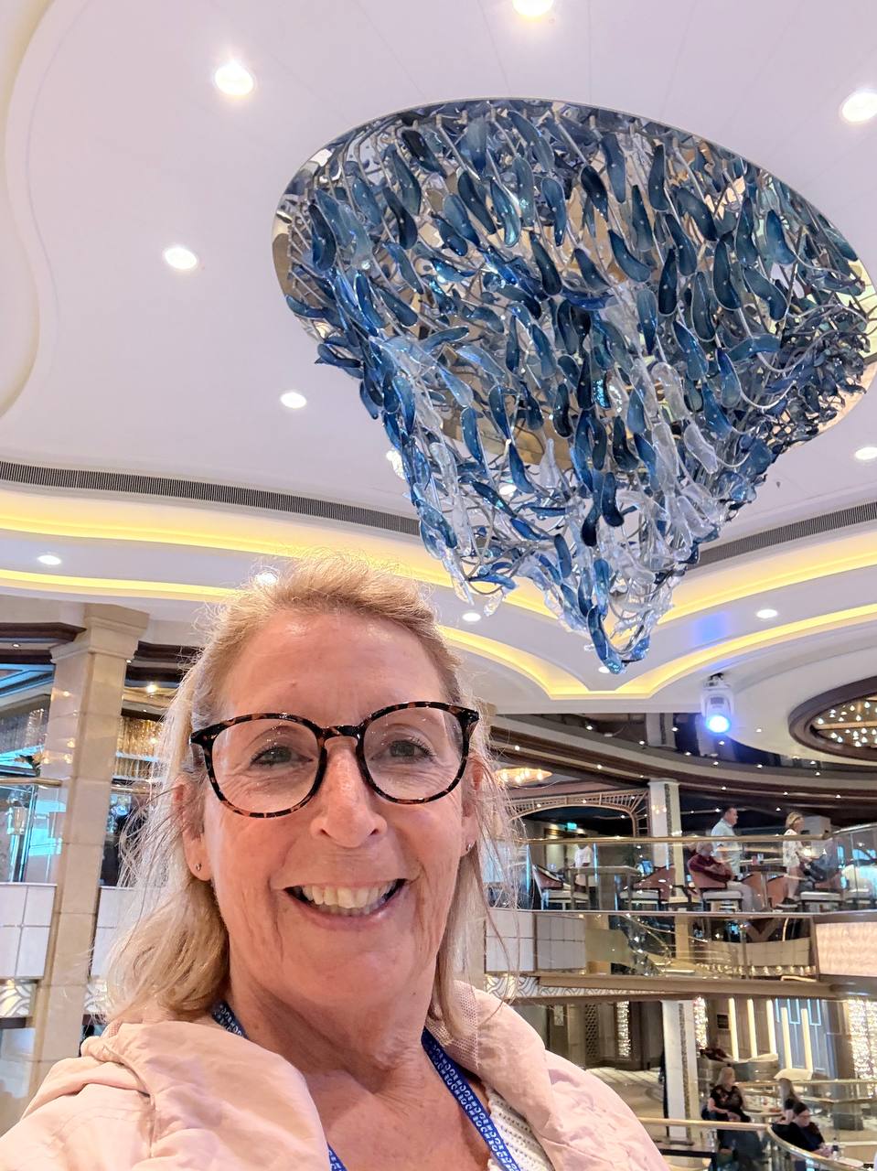 Smiling woman with the stunning blue chandelier in the cruise ship atrium