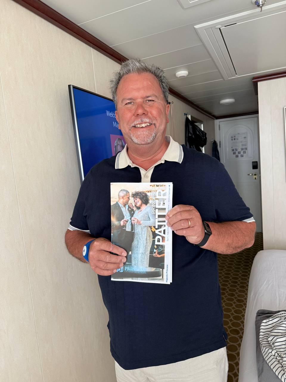 Man holding up Princess magazine celebrating 60 years in cabin