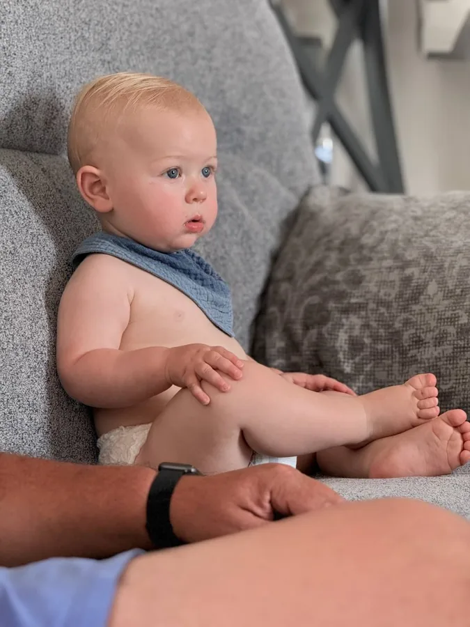 Theo snuggled up on the couch with a blue muslin cloth draped over his shoulders