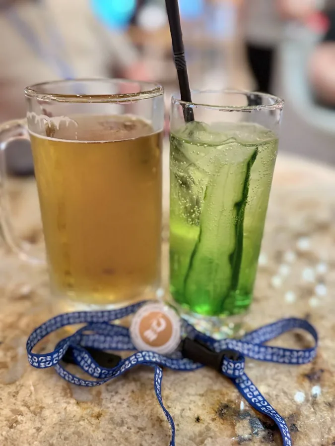 Two drinks and a cruise ID badge on a café counter - beer and green cocktail with Chicaco lanyard