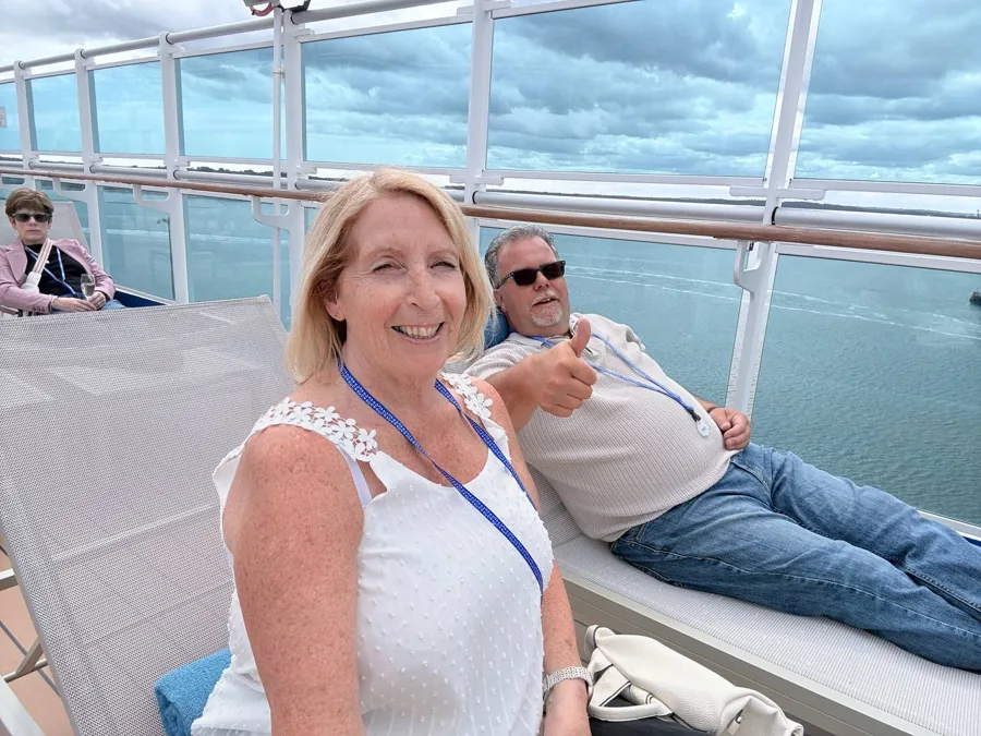 Three cruisegoers on deck at the sail away party - thumbs up, wine glass, and sea views