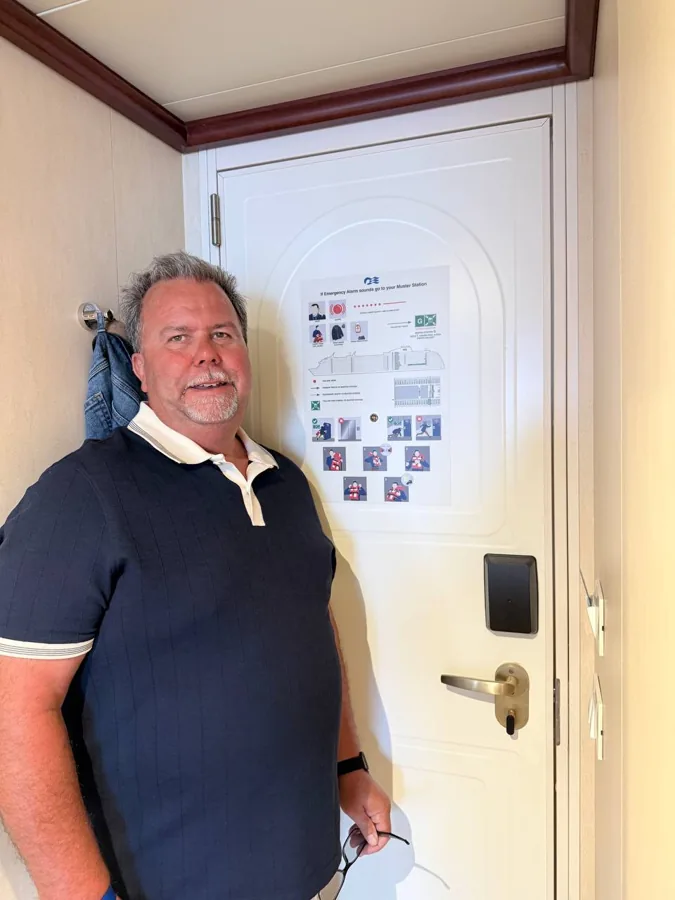 Man in corridor with cruise ship muster station poster
