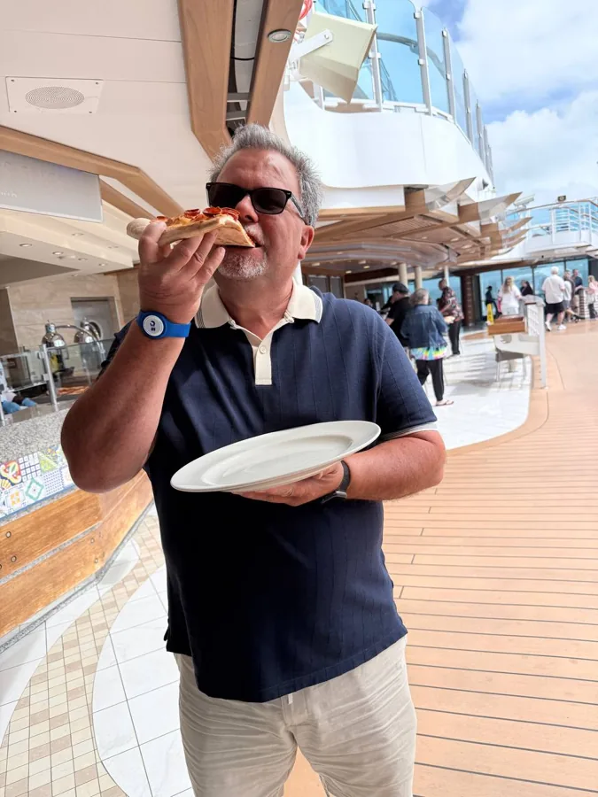 Man eating pizza slice on ship deck