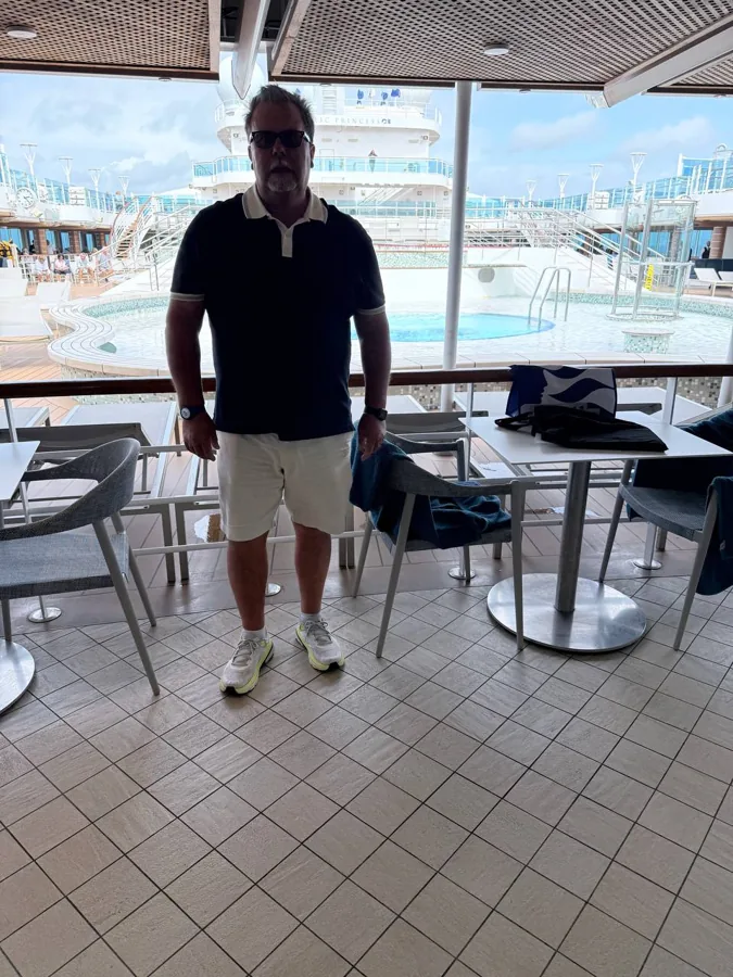 Man on ship deck with pool and ocean background